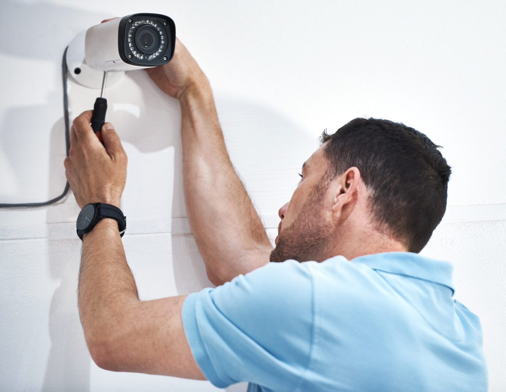 Mano presionando un lector biométrico de control de acceso en un edificio.